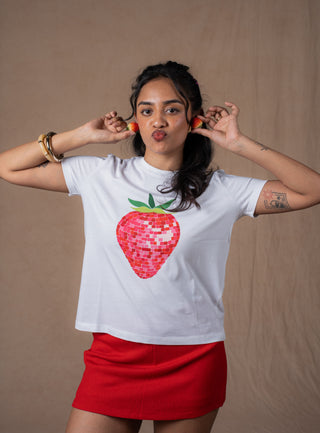 Model in a white t-shirt featuring a large disco-inspired red strawberry graphic on the front, paired with a red mini skirt