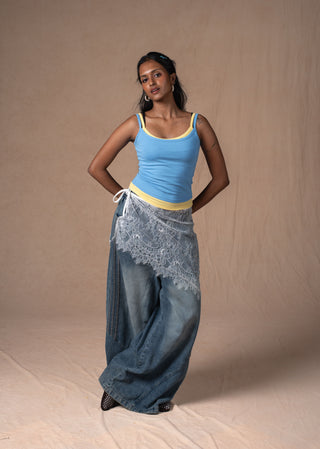A wearing the lemon sky double scoop tank in a light blue tank top with yellow trim, paired with wide-leg blue jeans and a sheer lace wrap
