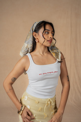 A model wearing a white ribbed tank top with red embroidered 'one spicy margarita, please' text on the chest