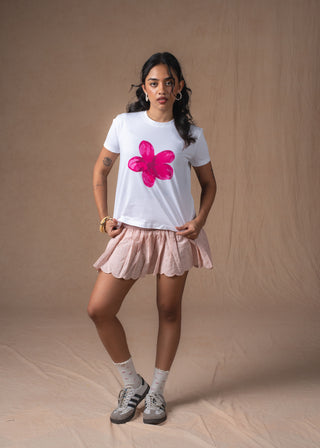 A model wearing a white short-sleeve pink bloom t-shirt with a large pink flower graphic on the front