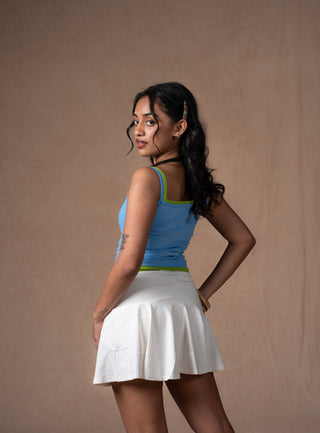 A model in a light blue seabreeze double-scoop tank top with lime green trim and a white pleated tennis skirt