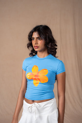 A light blue short-sleeve crop top with a large yellow and orange flower graphic on the front